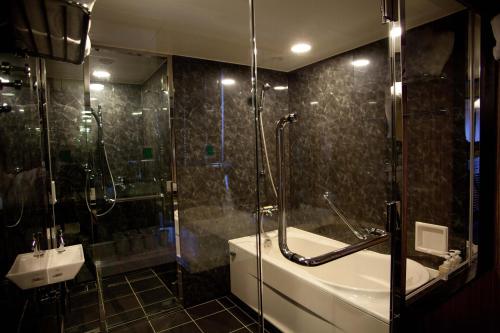 a bathroom with a shower and a tub and a sink at Hotel Monterey La Soeur Osaka in Osaka