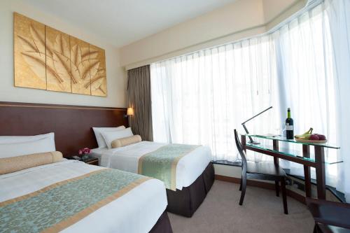 a hotel room with two beds and a desk and a window at Brighton Hotel Hong Kong in Hong Kong