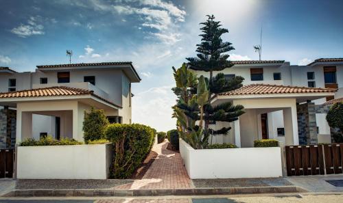 a house with a palm tree in front of it at Atlantis Gardens in Mazotos