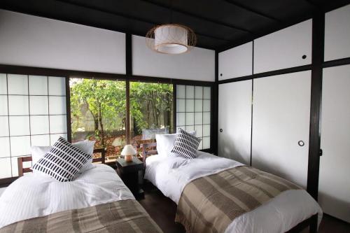 a bedroom with two beds and a large window at Yamaguchi House Annex, Private House with Onsen in Hakone