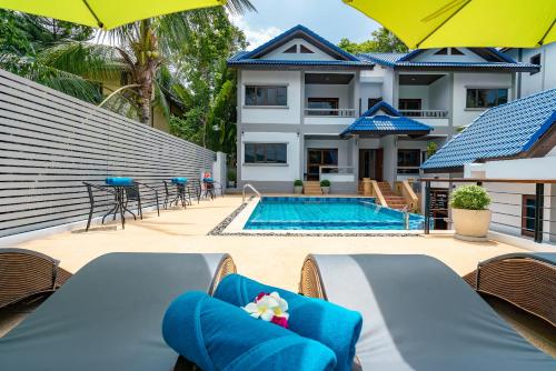 a pool with chairs and umbrellas next to a house at Chaweng Lakeview Residence in Chaweng