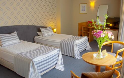 ein Hotelzimmer mit 2 Betten und einem Tisch mit Blumen in der Unterkunft Triada Hotel in Sofia