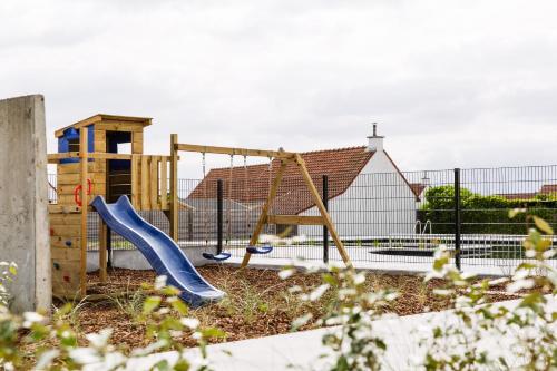 a playground with a blue slide in a yard at Zeegalm Bungalows in Middelkerke