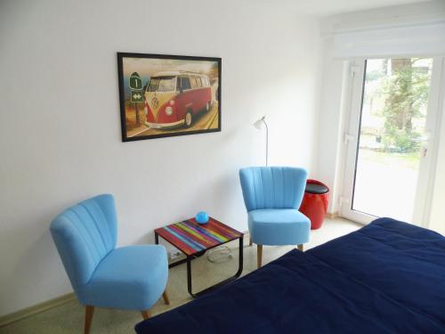 a bedroom with two blue chairs and a bed and a painting at Ferienwohnung am Rennsteig bei Eisenach - Ilona Schmidt in Wolfsburg-Unkeroda
