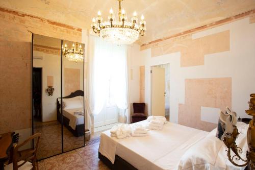 a bedroom with a bed and a mirror and a chandelier at La Maison in Siracusa