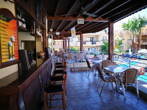 a restaurant with tables and chairs and a swimming pool at Pagona Holiday Apartments in Paphos City