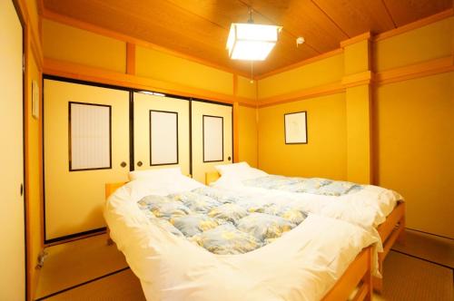 Cama grande en habitación con paredes amarillas en Takayama - House / Vacation STAY 34422, en Takayama