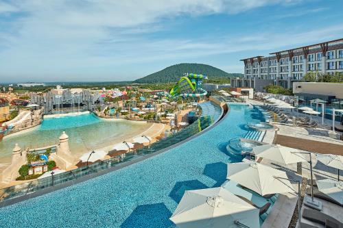 un resort con piscina e spiaggia con ombrelloni di Shinhwa Jeju Shinhwa World Hotels a Seogwipo