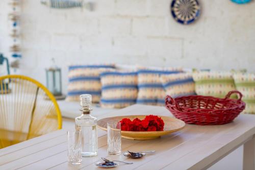 a table with a bowl of red flowers and a bottle at Kiko, the Coastline house in Kato Achaia
