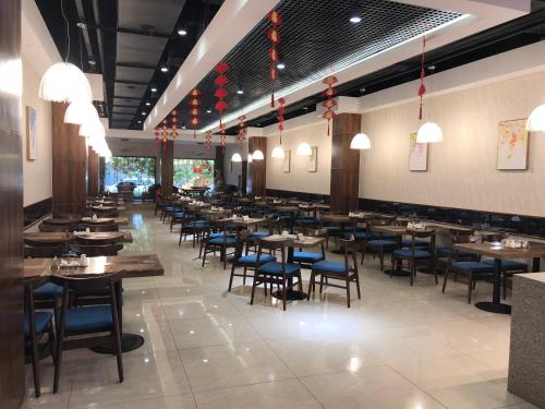 a dining room with tables and blue chairs at New Century Manju Hotel The Old Bund of Ningbo in Ningbo
