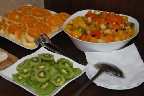a table with two plates of vegetables and a bowl of fruit at Hotel Arangues in Setúbal