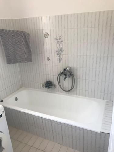 a white bath tub in a white tiled bathroom at Malom Vendégház in Szarvas