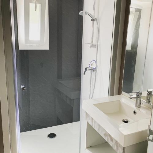 une salle de bain blanche avec un lavabo et une douche dans l'établissement Chalet 2 chambres en Bois dans les landes n34, à Tosse