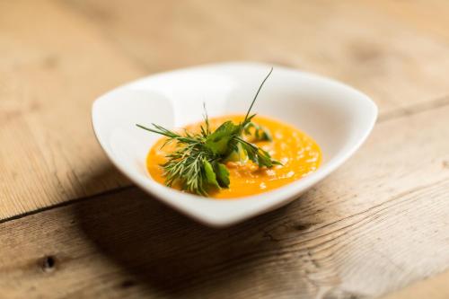 a white bowl of soup on a wooden table at Alpine Resort Sportalm in Sankt Leonhard im Pitztal