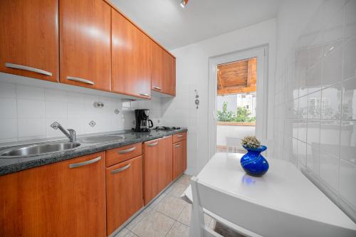 a kitchen with wooden cabinets and a blue vase on a counter at Apartmani Patača in Vodice