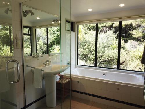 baño con bañera, lavabo y ventana en Te Huia, en Whangarei Heads