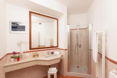 a bathroom with a sink and a shower with a mirror at Hotel Villa Domizia in Porto Santo Stefano