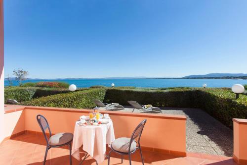 a table and chairs on a patio with the ocean in the background at Hotel Villa Domizia in Porto Santo Stefano