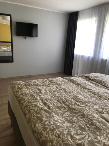 a bedroom with a bed and a television on the wall at Rómahegy Rendezvényház in Kaposvár