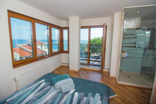 a bedroom with a bed and windows and a balcony at Breeze Guest House in Chernomorets