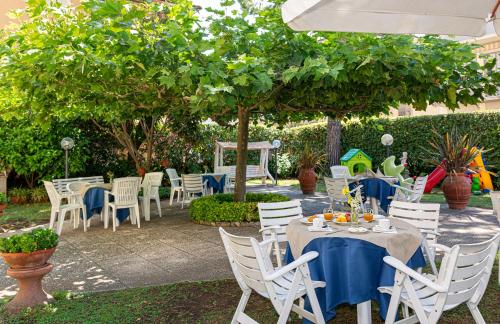 a group of tables and chairs under a tree at Hotel Perla Del Mare in Lido di Camaiore