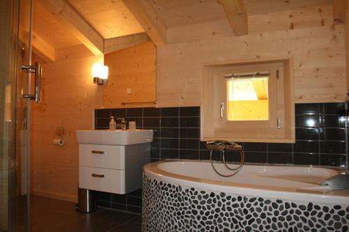 a bathroom with a bath tub and a sink at Chalet Courage in Champéry