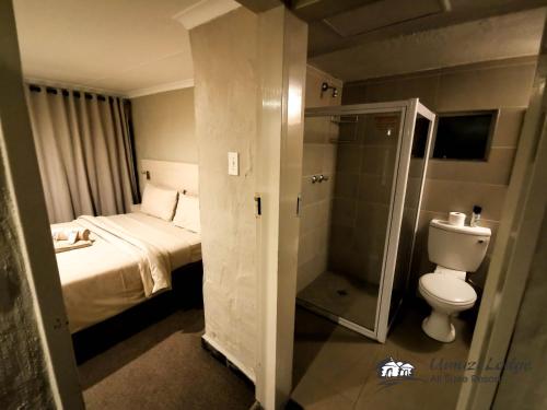 a bathroom with a bed and a toilet and a shower at Umuzi Lodge in Secunda