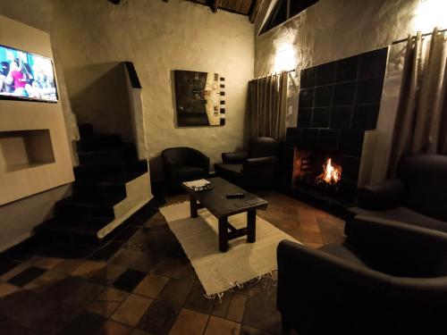 a living room with a fireplace and a tv at Umuzi Lodge in Secunda