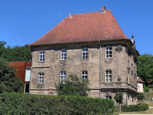 un ancien bâtiment en pierre avec un toit rouge dans l'établissement Wohnen in ehemaligen Kloster, à Lichtenfels