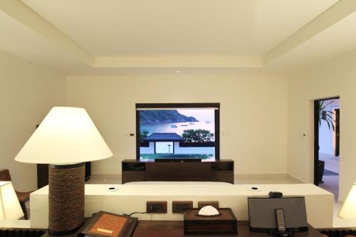 a living room with a tv and a lamp at The Racha - SHA Extra Plus in Ko Racha Yai