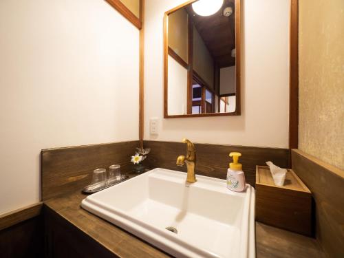 a bathroom with a sink and a mirror at Inase Otsu Machiya Bed and Breakfast in Otsu