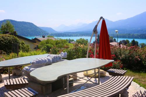a table with a bench and a red umbrella at Appartementhaus Franz Samonig in Drobollach am Faakersee