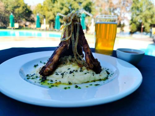 a plate of food and a glass of beer at Umuzi Lodge in Secunda