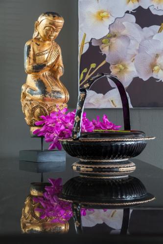a statue of a woman and flowers on a table at The Pavilions Phuket in Bang Tao Beach