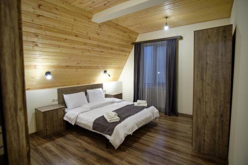 a bedroom with a large bed and a wooden ceiling at Hotel TWINS Achkhoti in Stepantsminda
