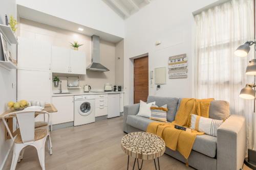 a living room with a couch and a kitchen at La buhardilla in Seville