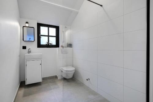 een witte badkamer met een toilet en een raam bij Zandvoort Paradise Boutique Chambre in Zandvoort