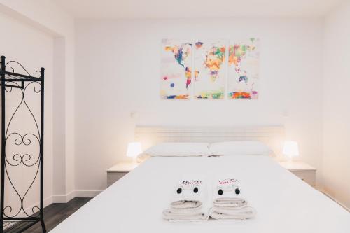 a white bedroom with a white bed with two masks at Aiara apartment by People Rentals in Bilbao