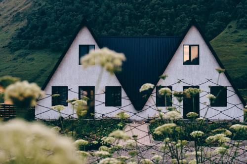 a white house with a black roof and windows at Hotel TWINS Achkhoti in Stepantsminda