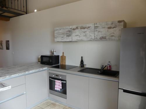 a kitchen with white cabinets and a sink and a refrigerator at Domaine de la Vidalle in Vendres