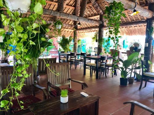 美奈的住宿－MiNhon Hotel Muine，一间设有桌椅的餐厅,种植了植物
