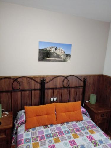 a bed with an orange pillow in a bedroom at Casa Rural Al-Mofrag y Apartamentos El Mirador de Monfragüe in Villarreal de San Carlos