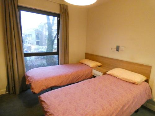 um quarto de hotel com duas camas e uma janela em Newington Court (Stoke Newington) em Londres