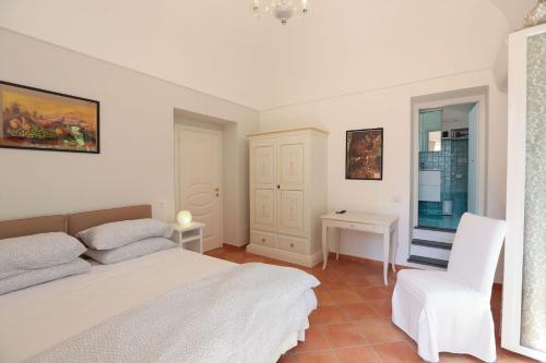 a bedroom with a white bed and a white chair at Casa Ponticeto in Ravello