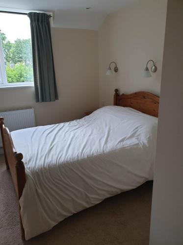 a bedroom with a bed with white sheets and a window at the old red lion in Bruton