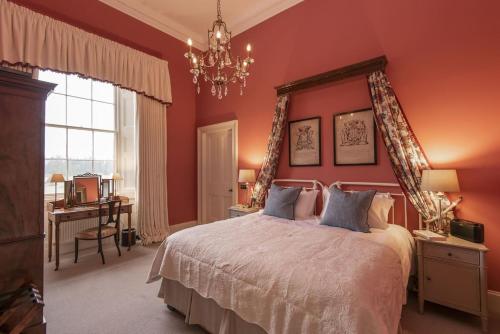 1 dormitorio con paredes rojas y 1 cama con lámpara de araña. en The Earl & Countess at Thirlestane Castle en Lauder