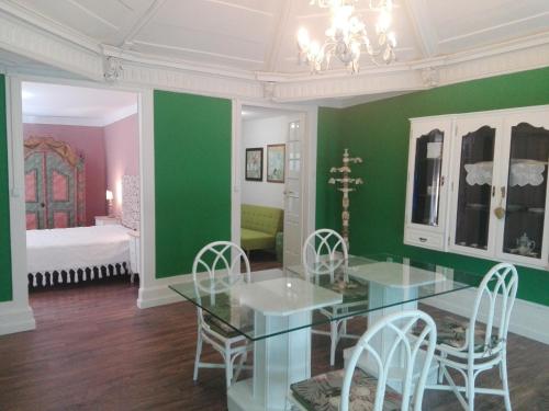 Casa da Varanda Verde في فيلا ريال: غرفة طعام بجدران خضراء وطاولة وكراسي