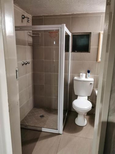 a bathroom with a toilet and a shower with a glass door at Umuzi Lodge in Secunda