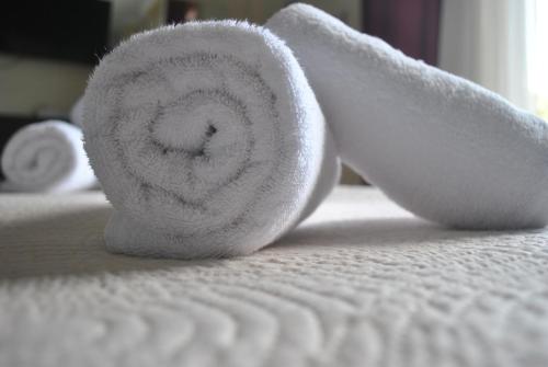 a roll of white towel sitting on a bed at Alexander Apartments in Alexandroupoli