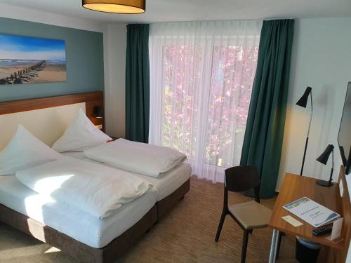 a bedroom with a bed and a desk and a window at Hotel Friesische Wehde in Bockhorn